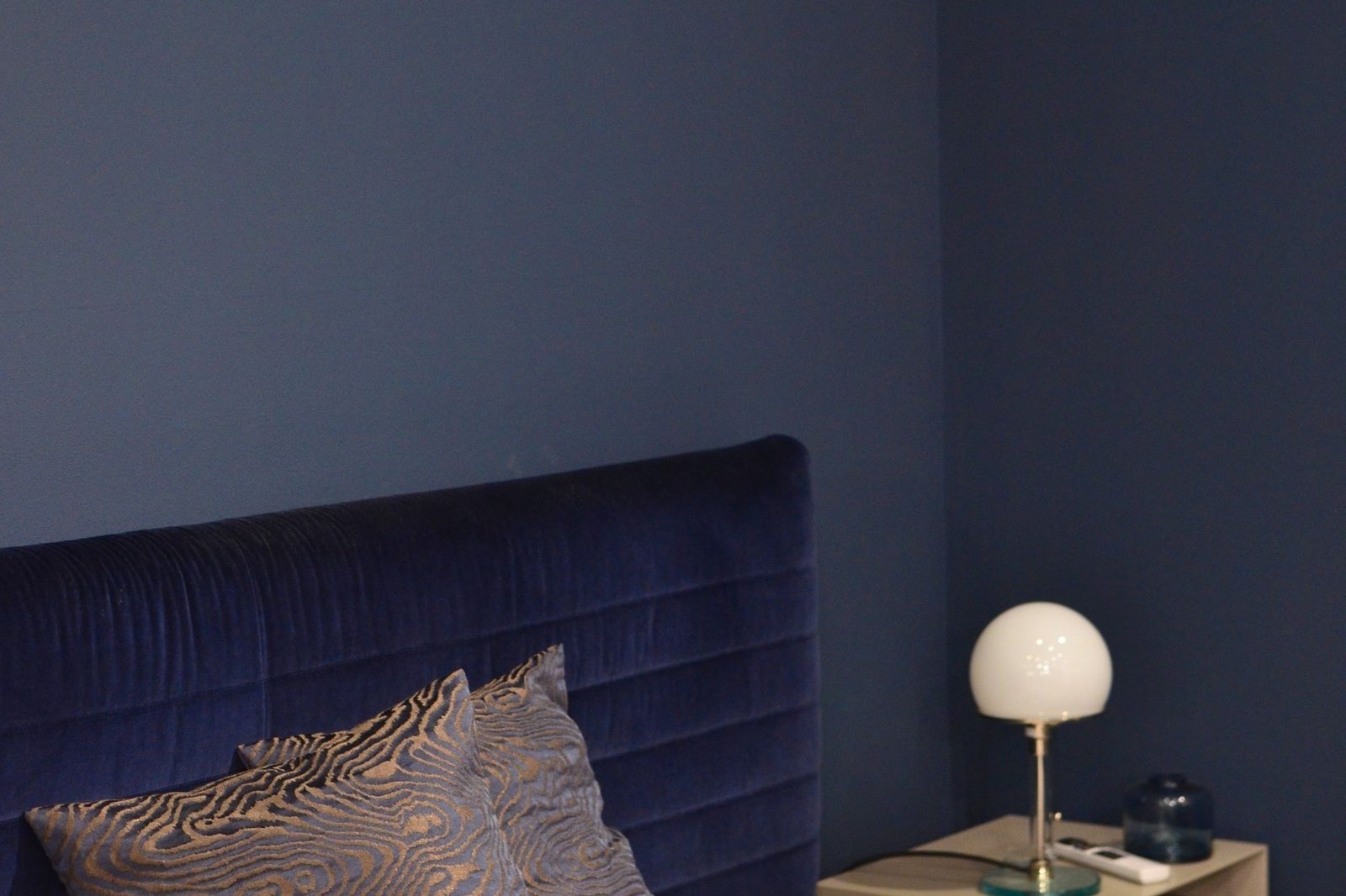 A bedroom with a deep navy panelled wall behind the bed