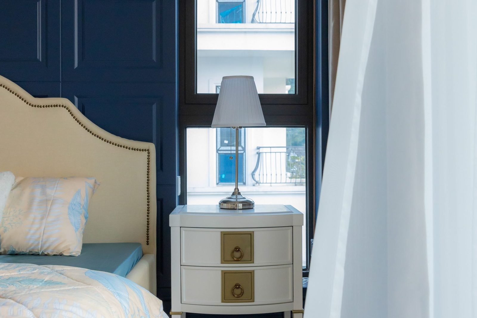 A soft blue and cream bedroom with a curved headboard and bedside lamps