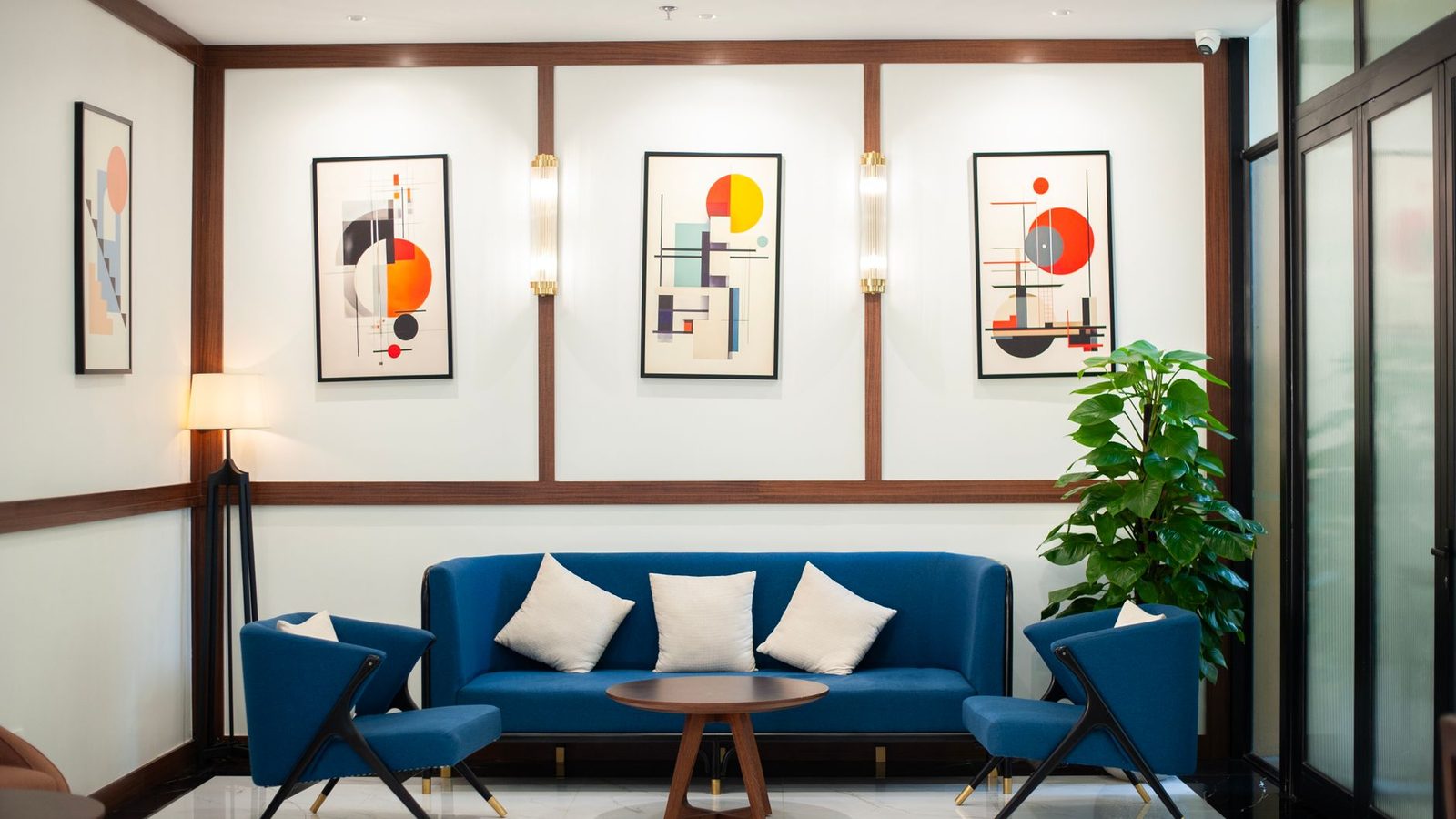 A living room with a deep blue sofa, a gallery wall of framed prints and warm wood floors