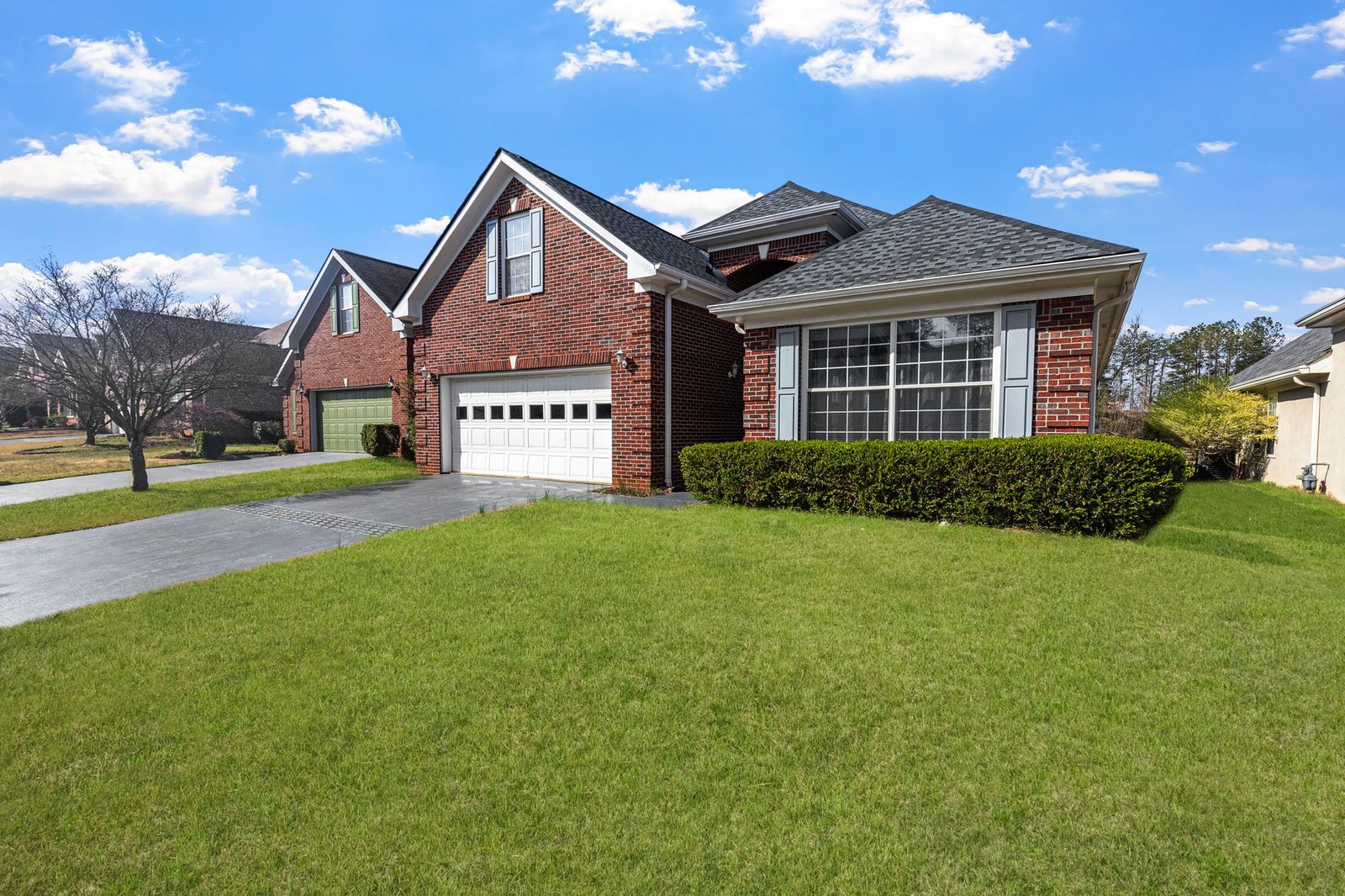 A brick suburban house with a front lawn under a blue sky