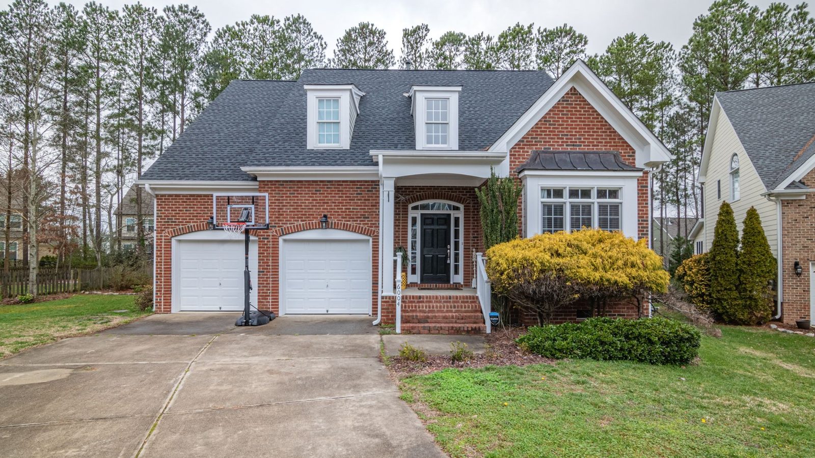A brick and siding suburban house with a two-car garage and a front lawn