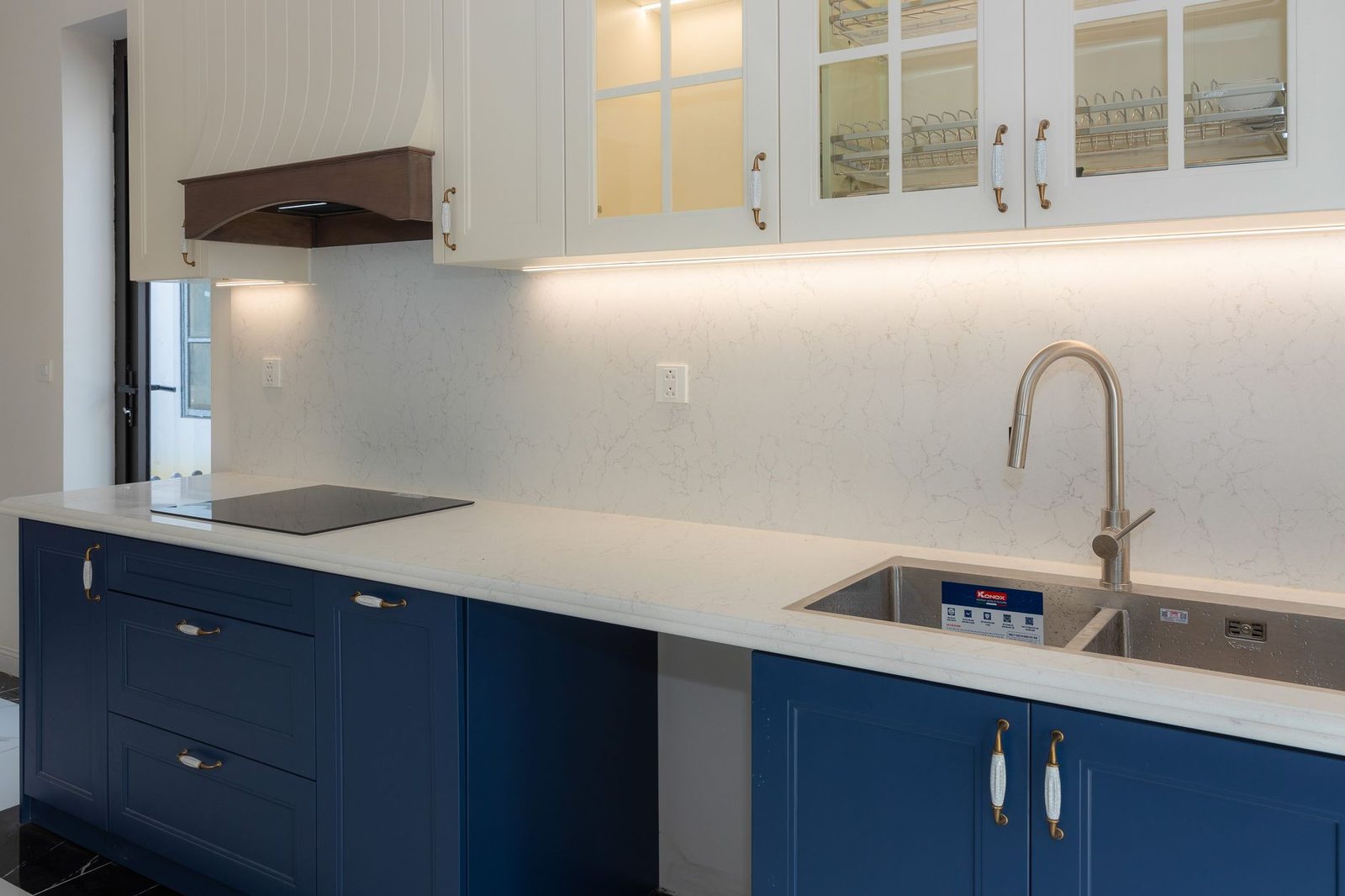 A kitchen with navy lower cabinets and white worktops