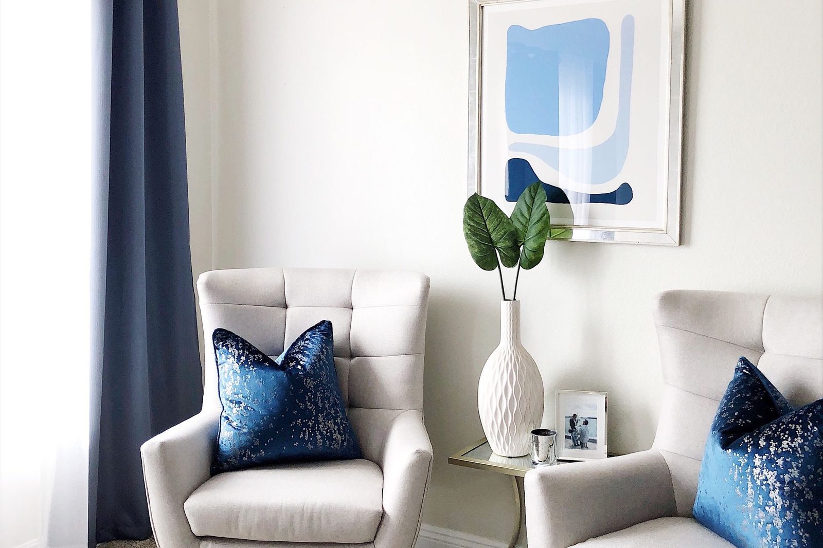 A living room with cream armchairs, navy cushions and navy curtains