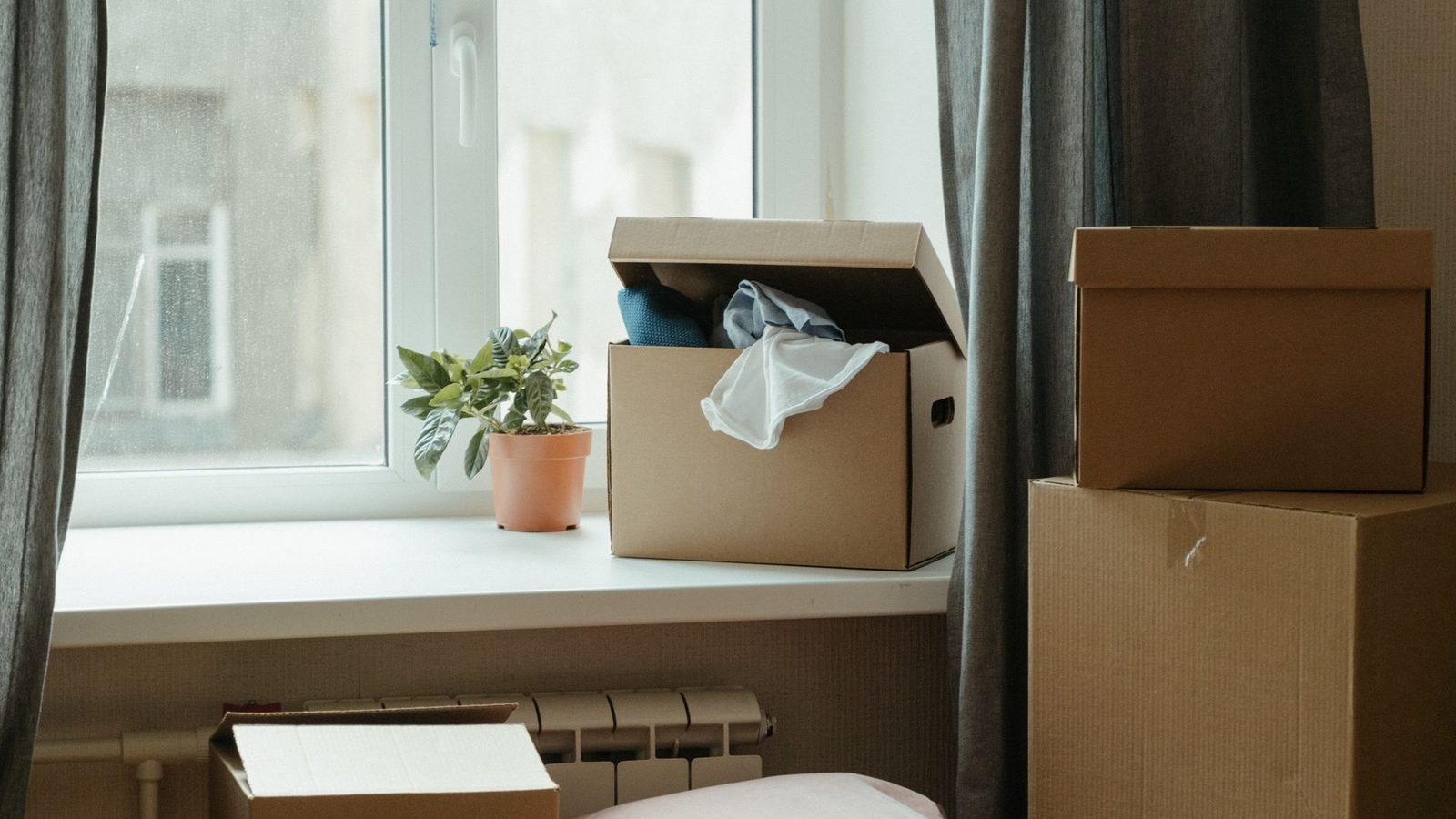 Cardboard moving boxes stacked by a window in an empty room