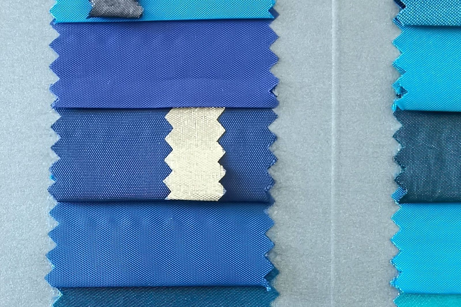 Fabric swatches in a graduated range of blues laid out in a row